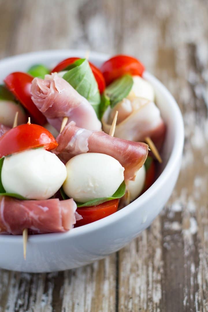 A white bowl of Prosciutto and Mozzarella Skewers.