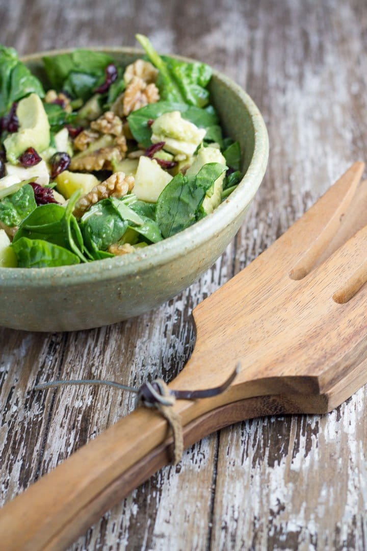 A bowl of salad with salad servers