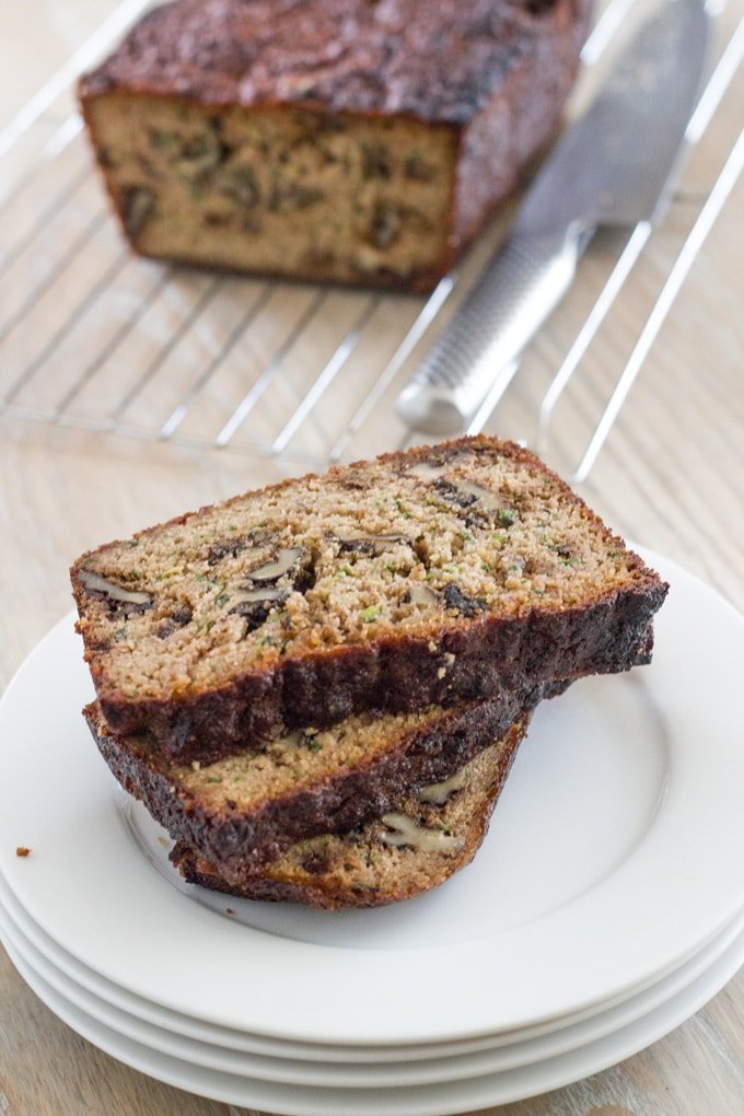 Slices of the Zucchini walnut bread on a plate with the loaf in the background.