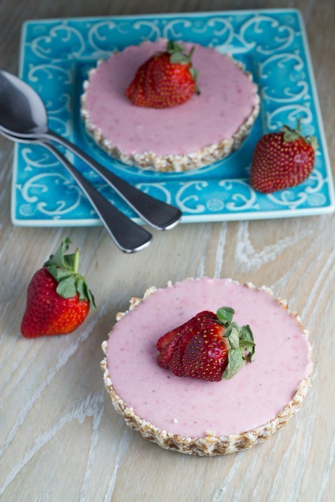 Two raw strawberry mousse tarts with fresh strawberries on top.