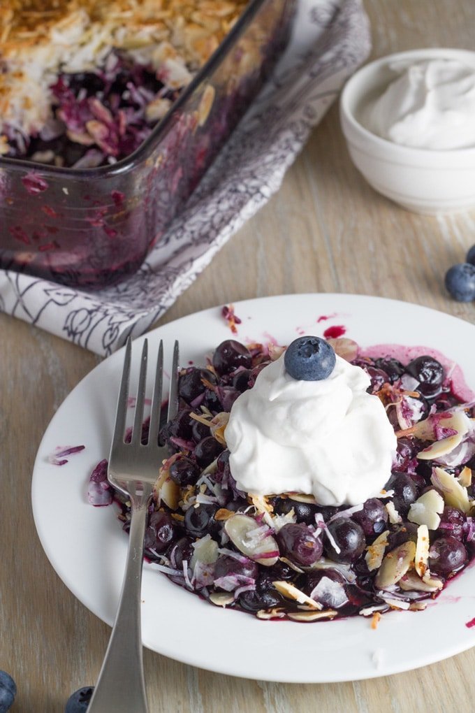 Gluten free crumble on a plate topped with whipped cream.