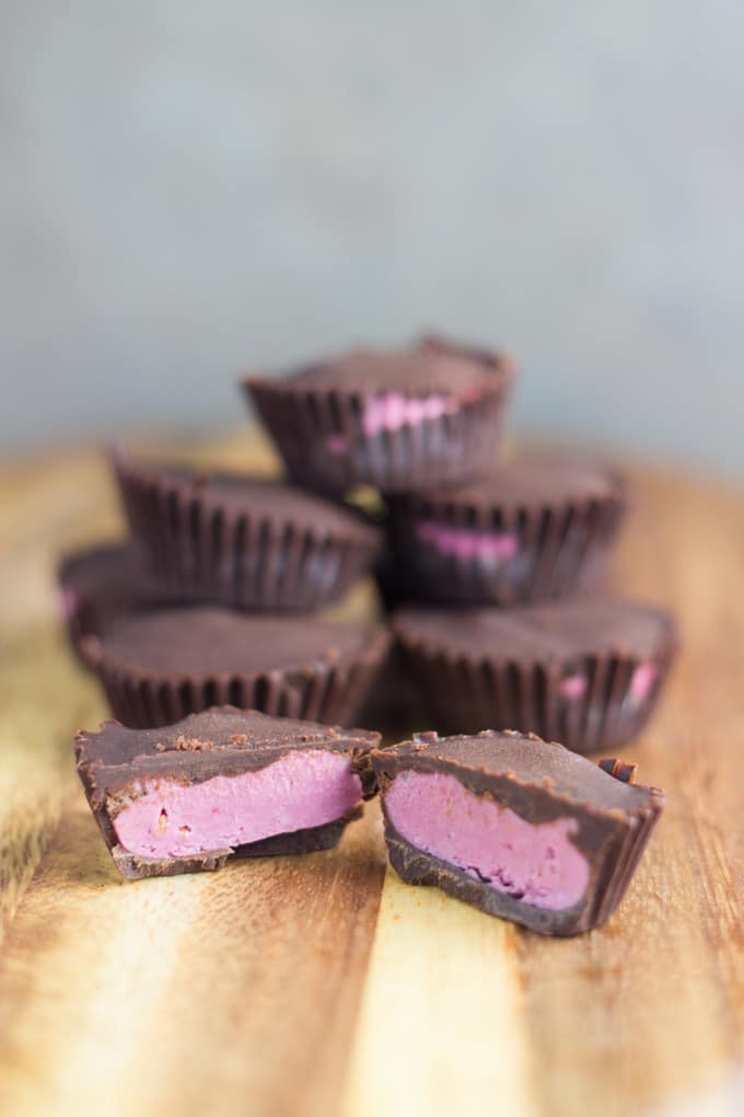 Mini raspberry chocolates on a board with the front chocolate cut in half.
