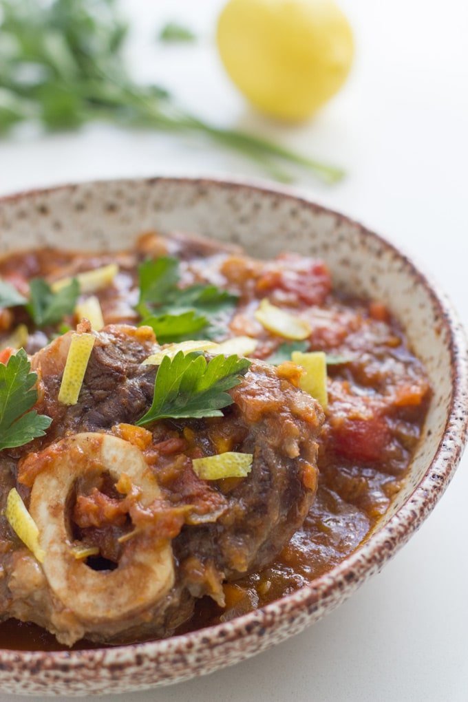 A bowl of Slow Cooker Osso topped with parsley and lemon rind.