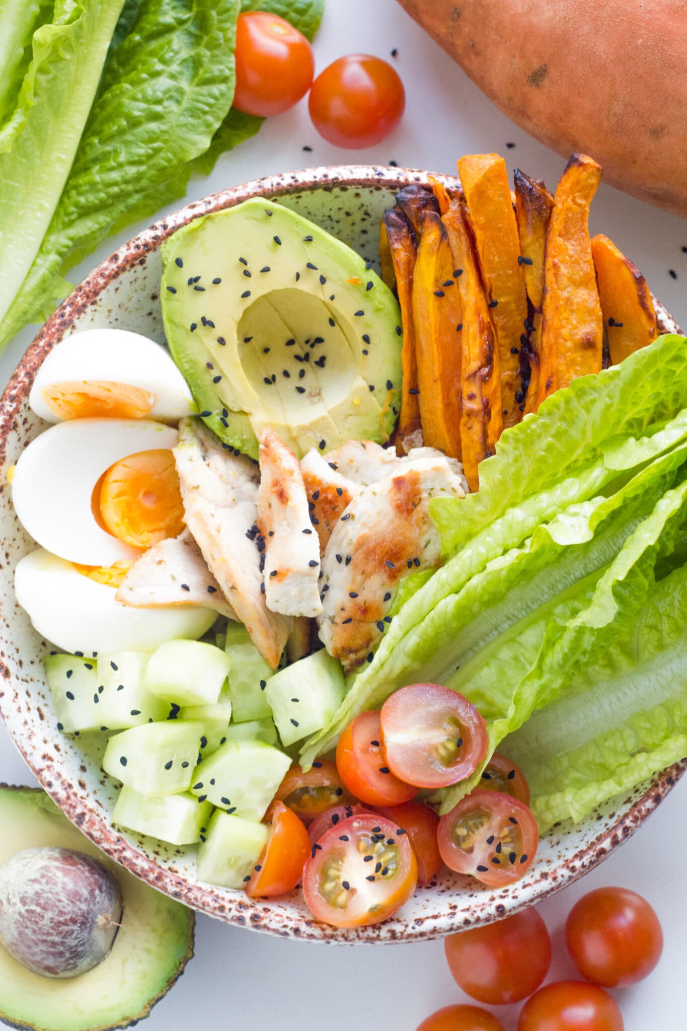 photo of the lemon garlic chicken buddha bowl with sweet potato, avocado, egg, cucumber, cherry tomato, lettuce and chicken.
