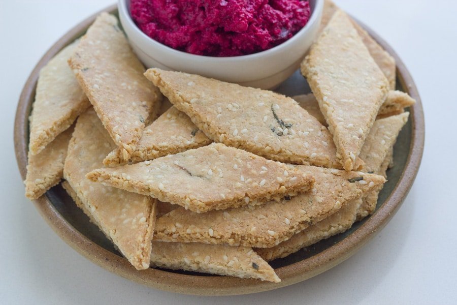 Rosemary crackers on a plate with some beetroot dip.