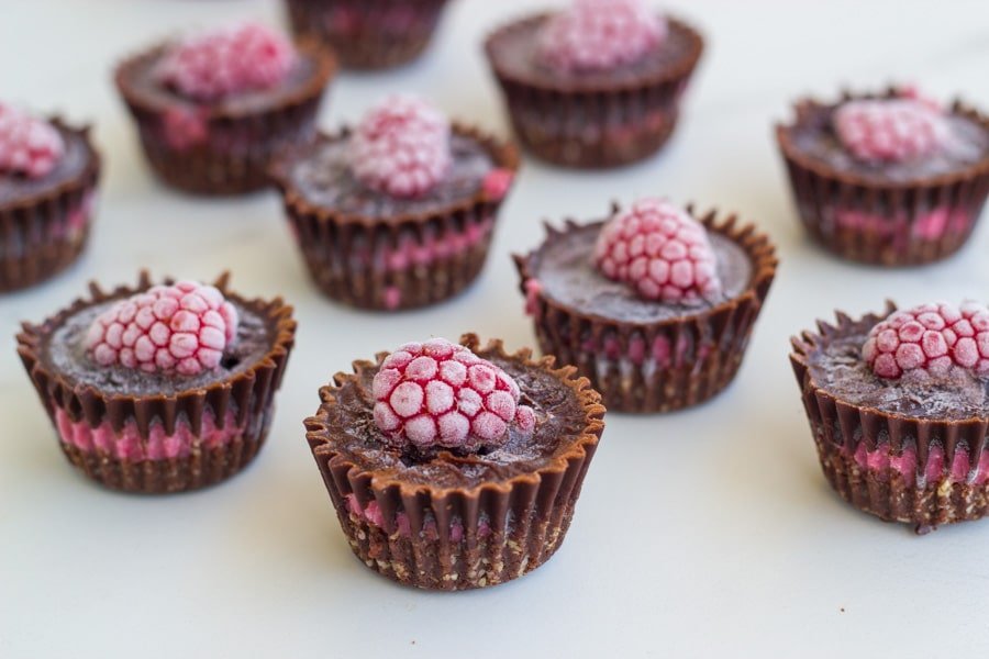 Several raspberry chocolates on white board.