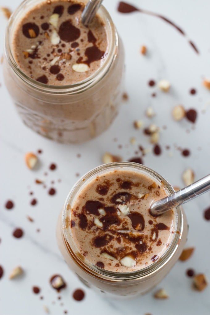 Two smoothies in glasses with metal straws