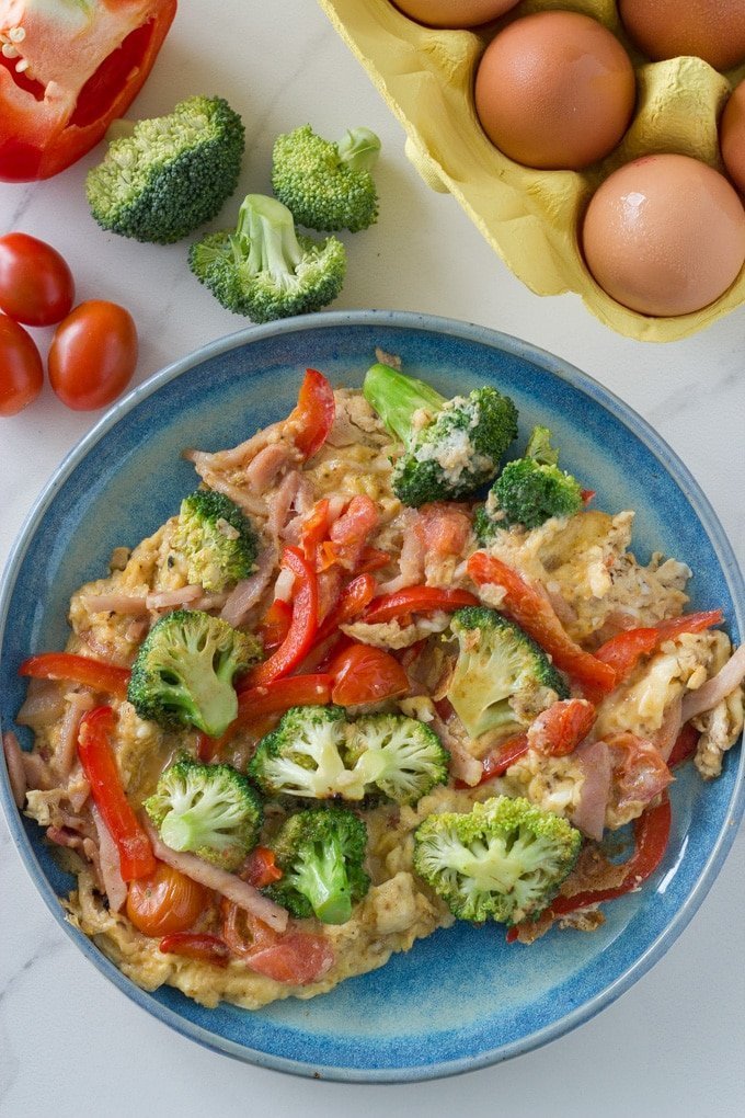 Vegetable egg scramble on a plate with the ingredients next to it. 