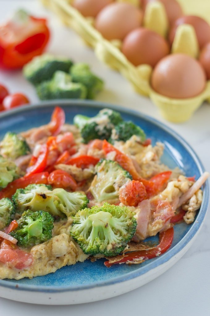 Breakfast scramble on a plate with the ingredients in the background.