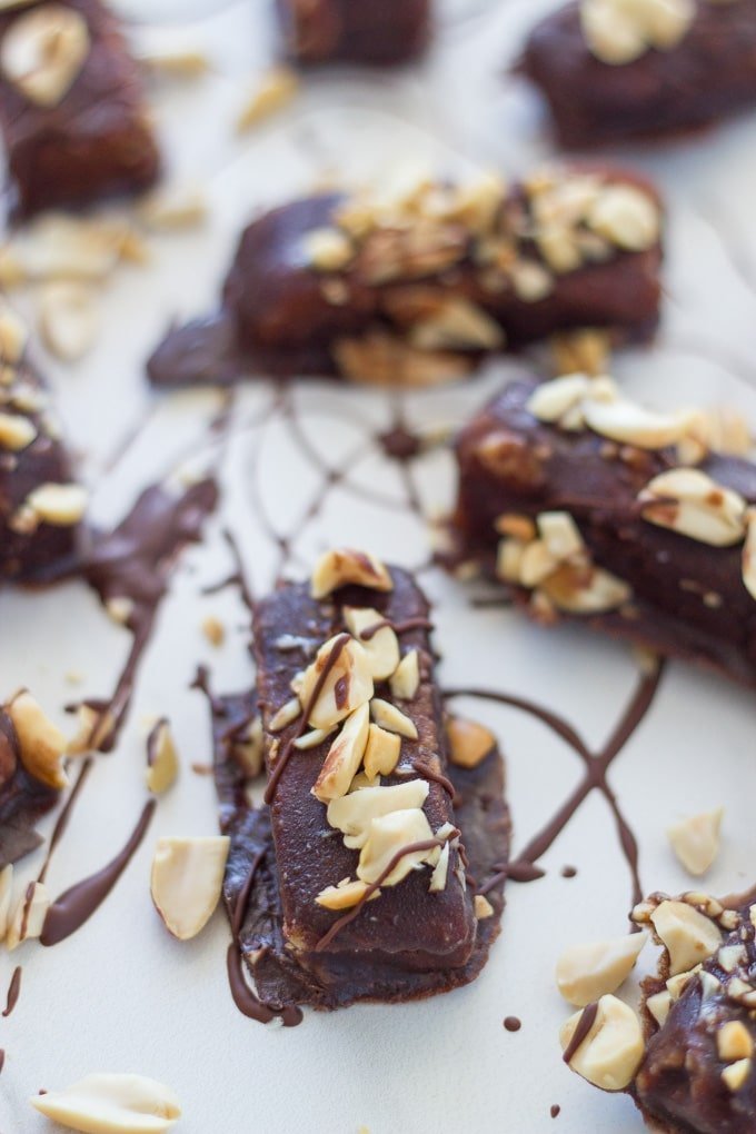 Caramel Peanut Butter bars on white board with peanuts and chocolate swirled over them