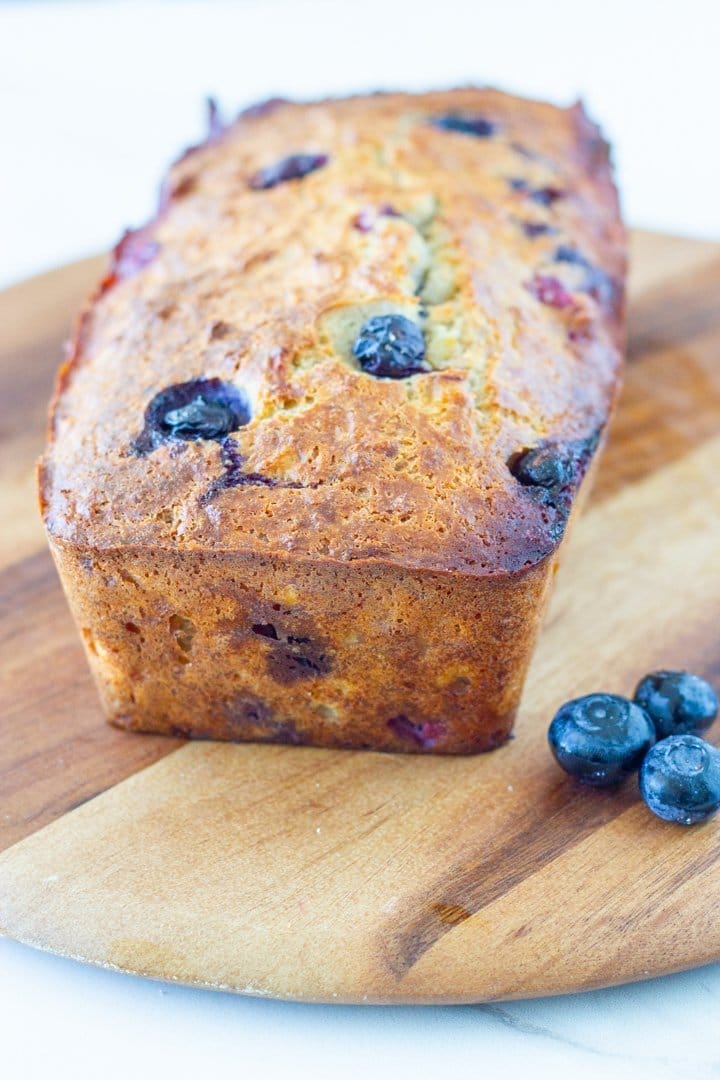 low carb banana and blueberry bread on a wooden board with blueberries