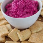 beetroot hummus in a bowl with crackers in front of it