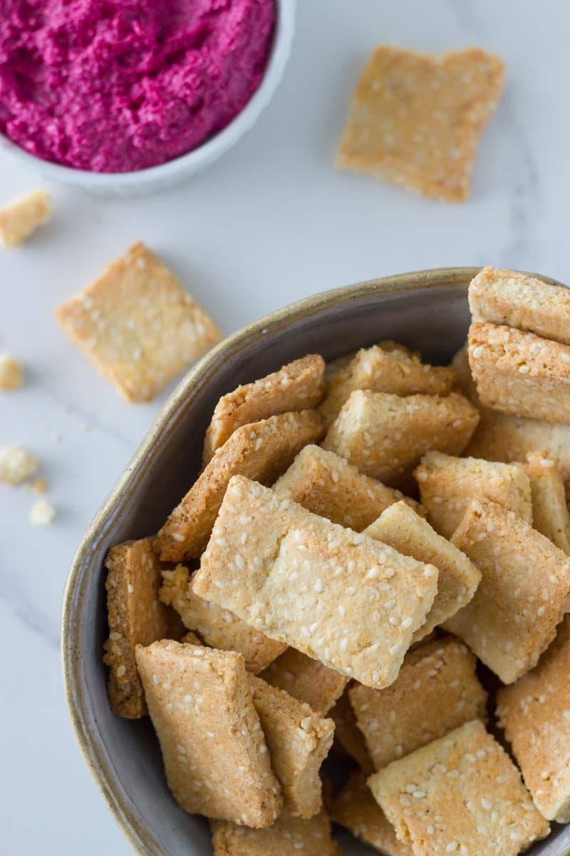 home made crackers in a bowl with beetroot hummus is a smaller bowl