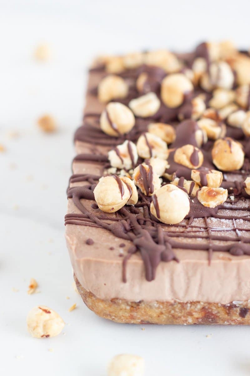 Close up of the slice emphasizing the drizzled chocolate and hazelnuts on top.