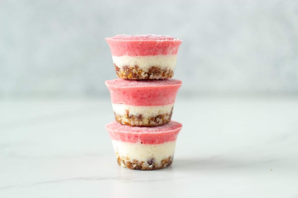 Stack of three raw dessert bites of white background.