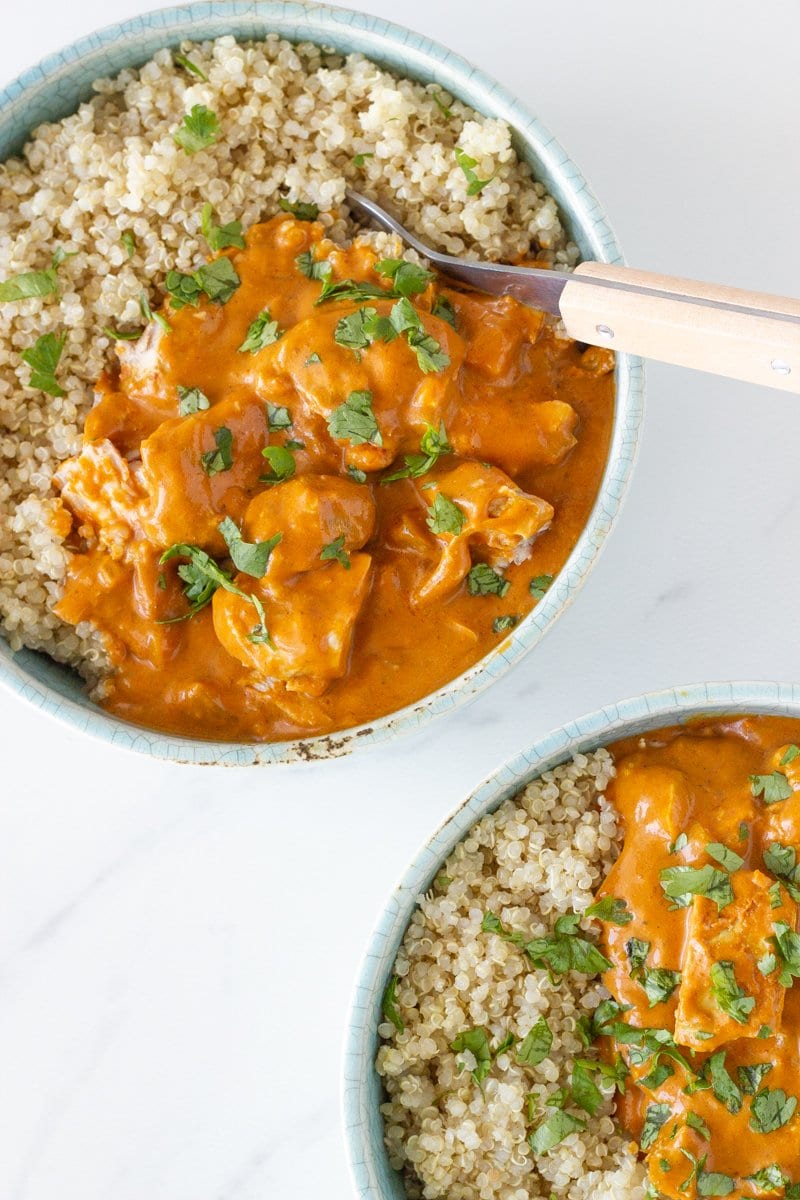 Two bowls of slow cooker chicken tikka ma.sala with some fresh coriander on top/