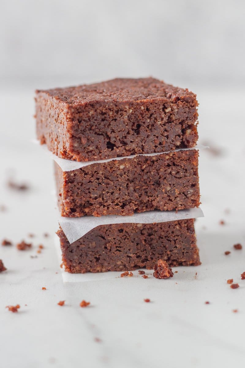 Stack of gluten free brownies with baking paper in between each slice. 