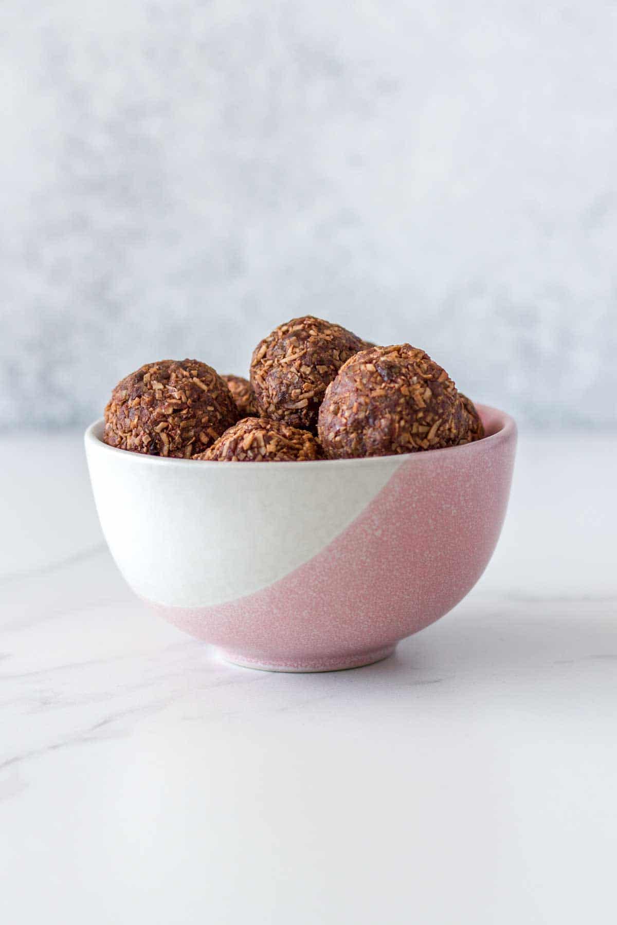 A pink and white bowl of bliss balls.