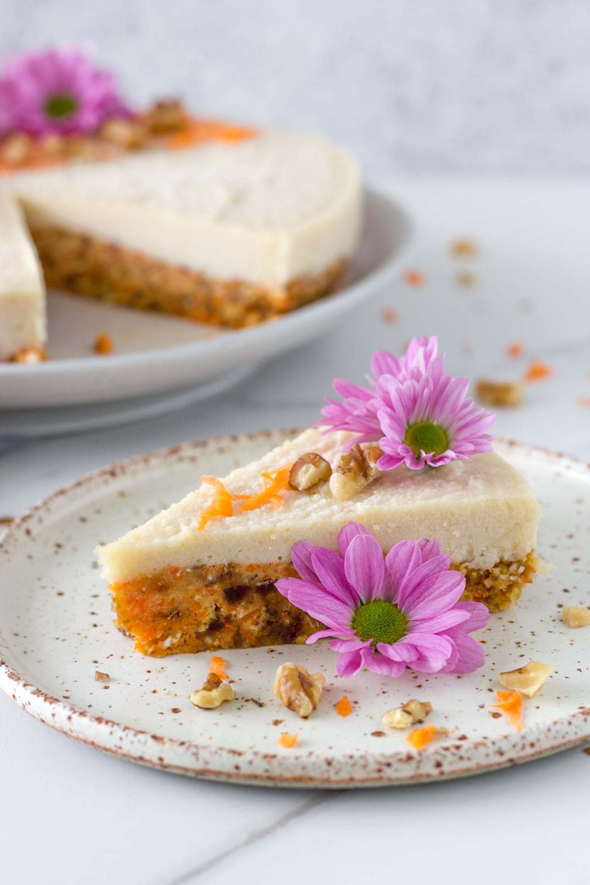 A piece of the Raw Vegan Carrot Cake with the cake in the background.