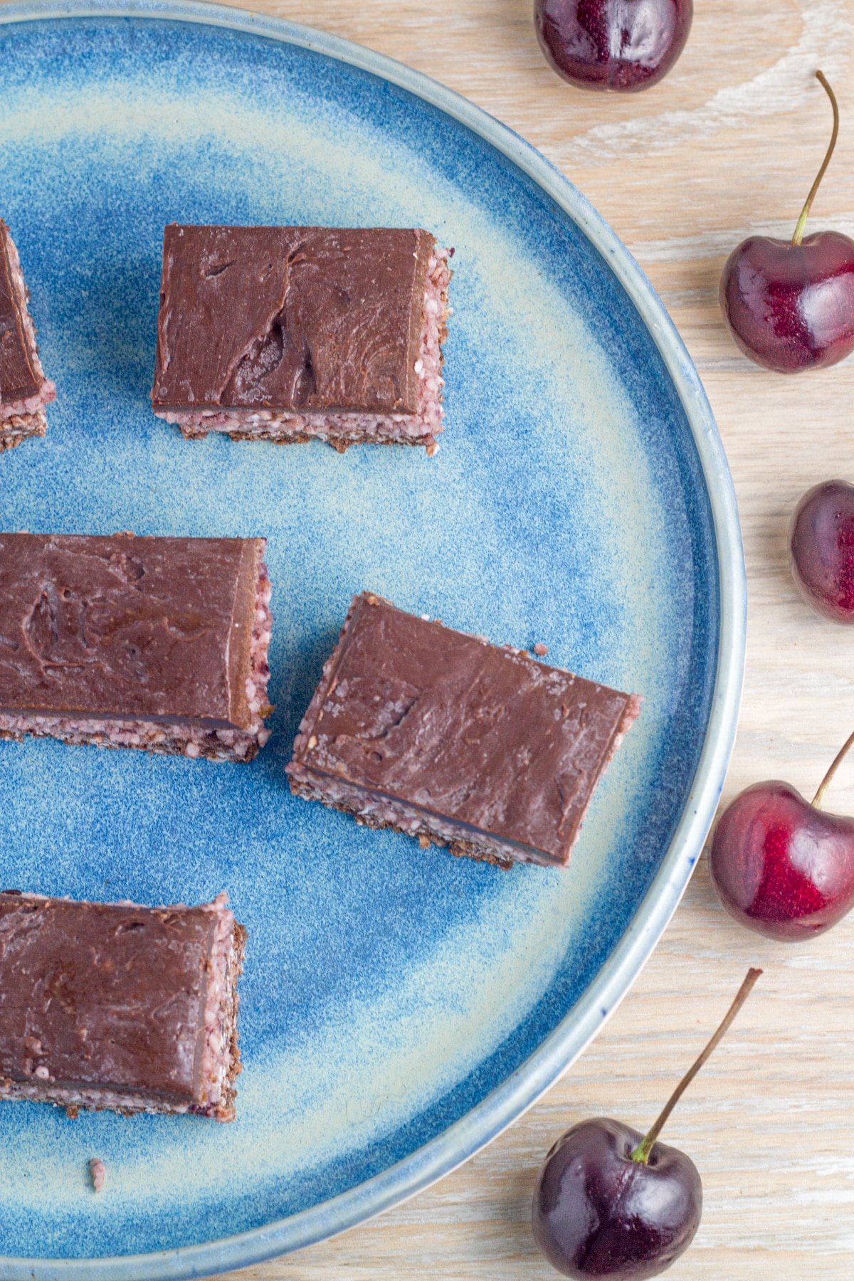 Pieces of Raw Cherry Ripe Slice on a blue plate.