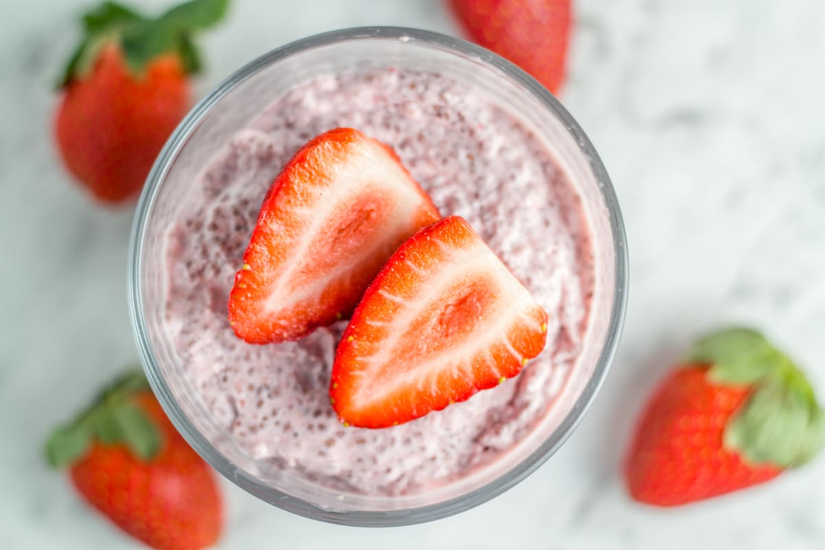 Chia Pudding with strawberries on top and surround the glass.