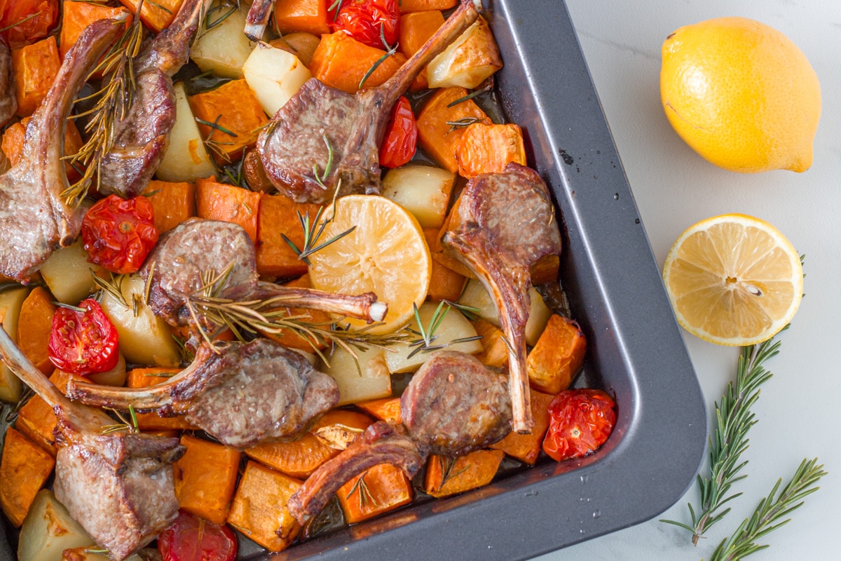 Tray of lamb and vegetables with lemon and fresh rosemary. 