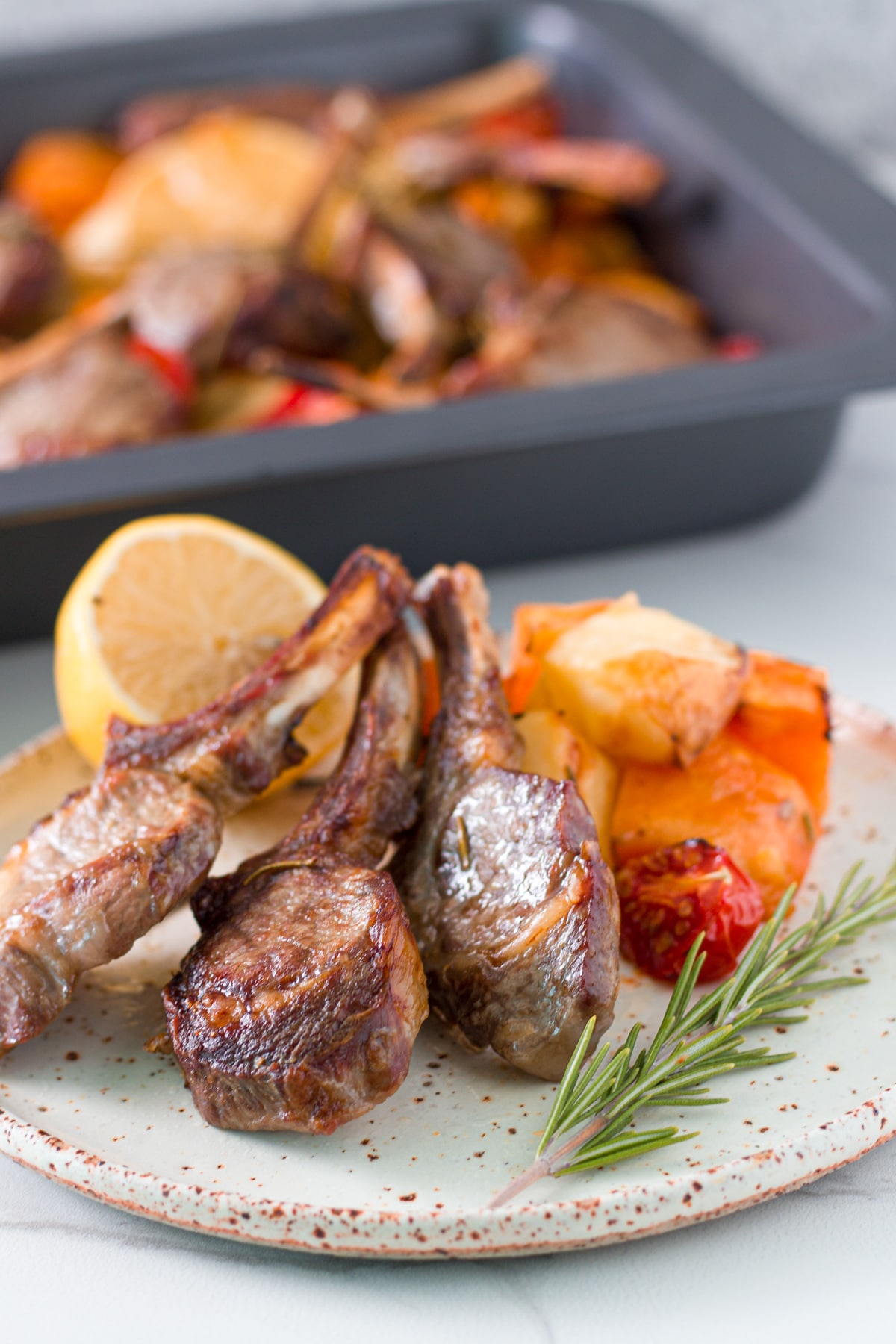 The oven lamb cutlets with baked potatoes and tomatoes in a baking tray ready to eat.