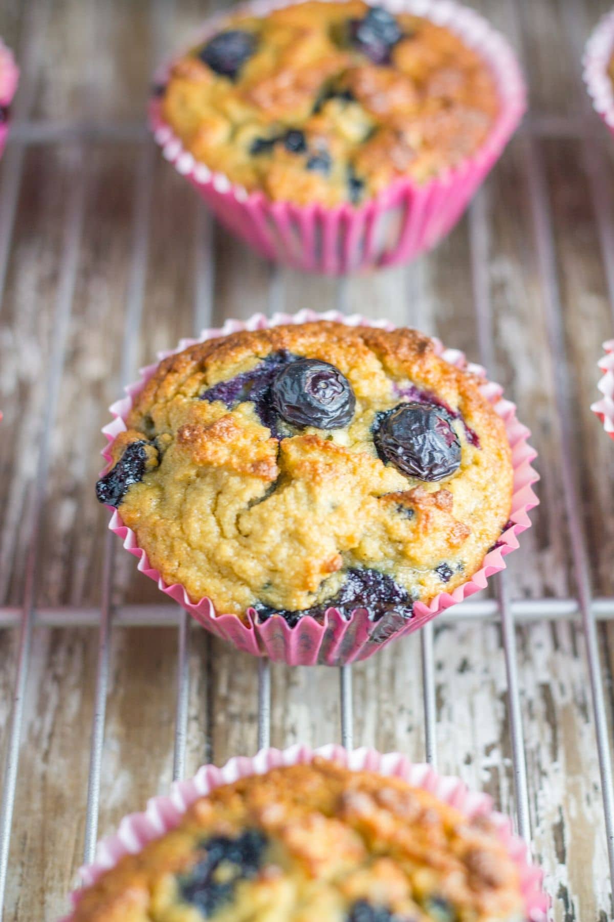 Dairy free blueberry muffins on a cooling tray on top of a wooden board.