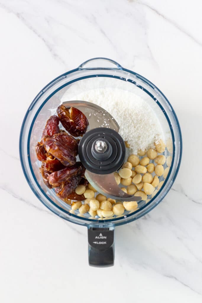 picture of food processor bowl with the base ingredients – dates, shredded coconut and macadamias.