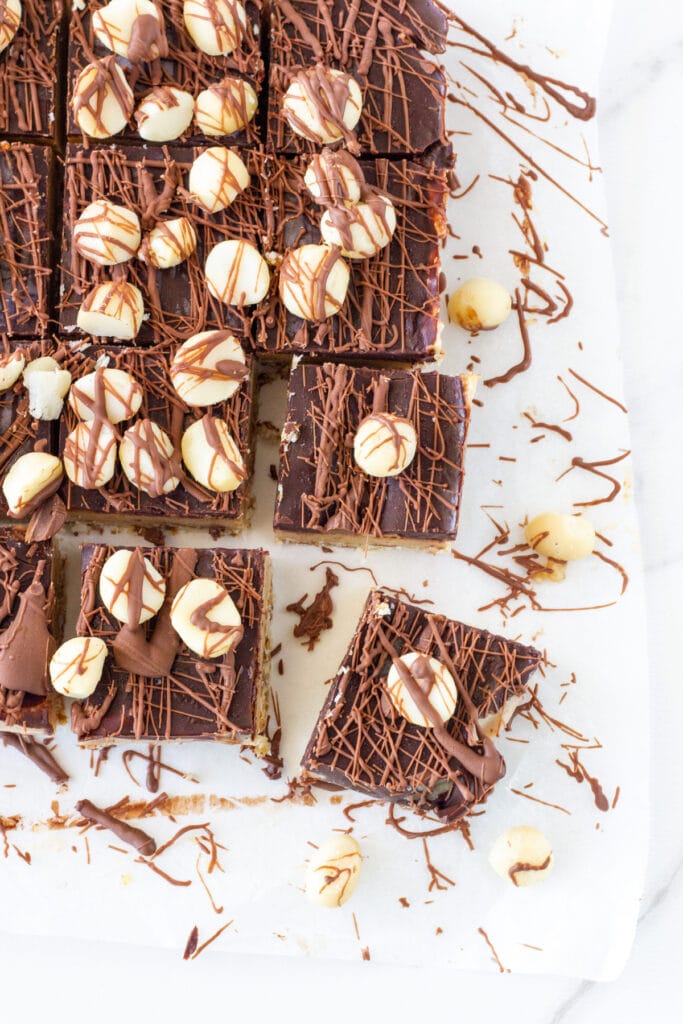 Caramel Slice cut into pieces on white baking paper. 