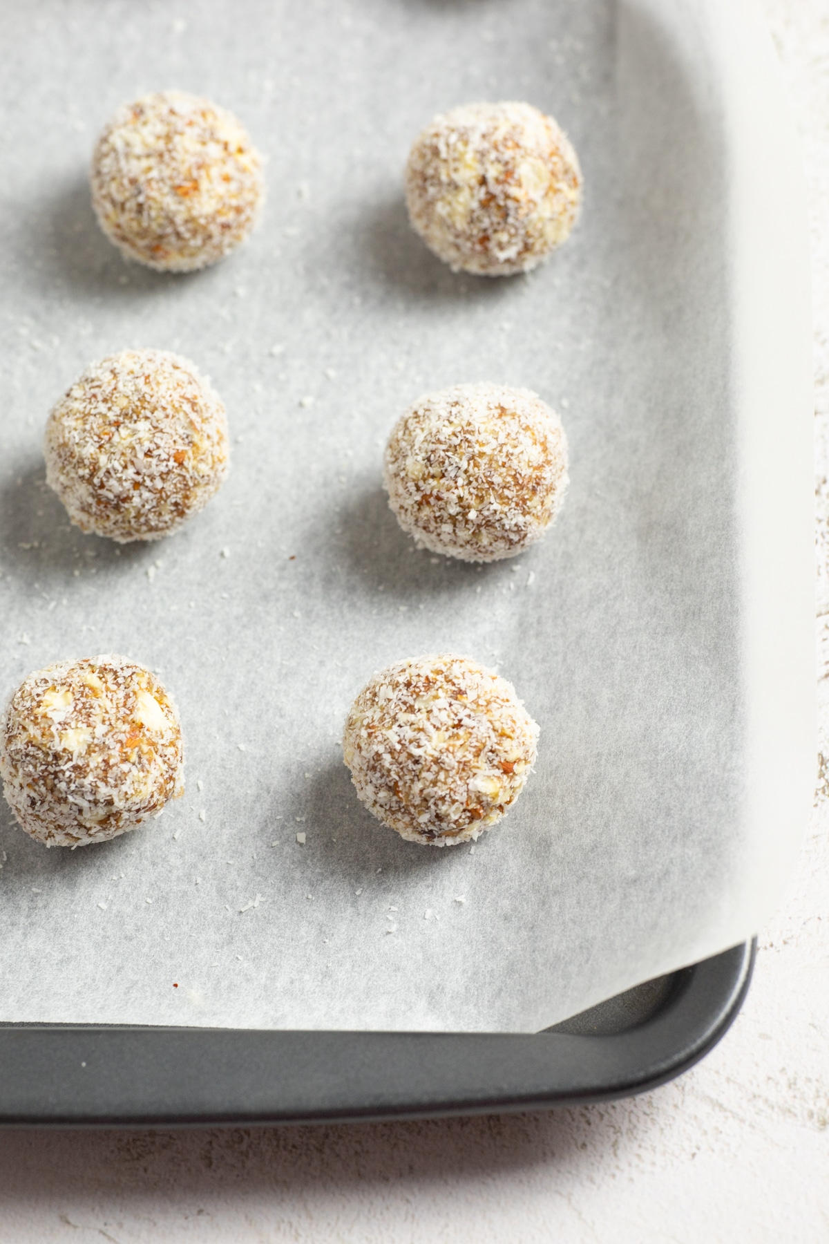 Close up of the bliss balls on a lined baking tray.