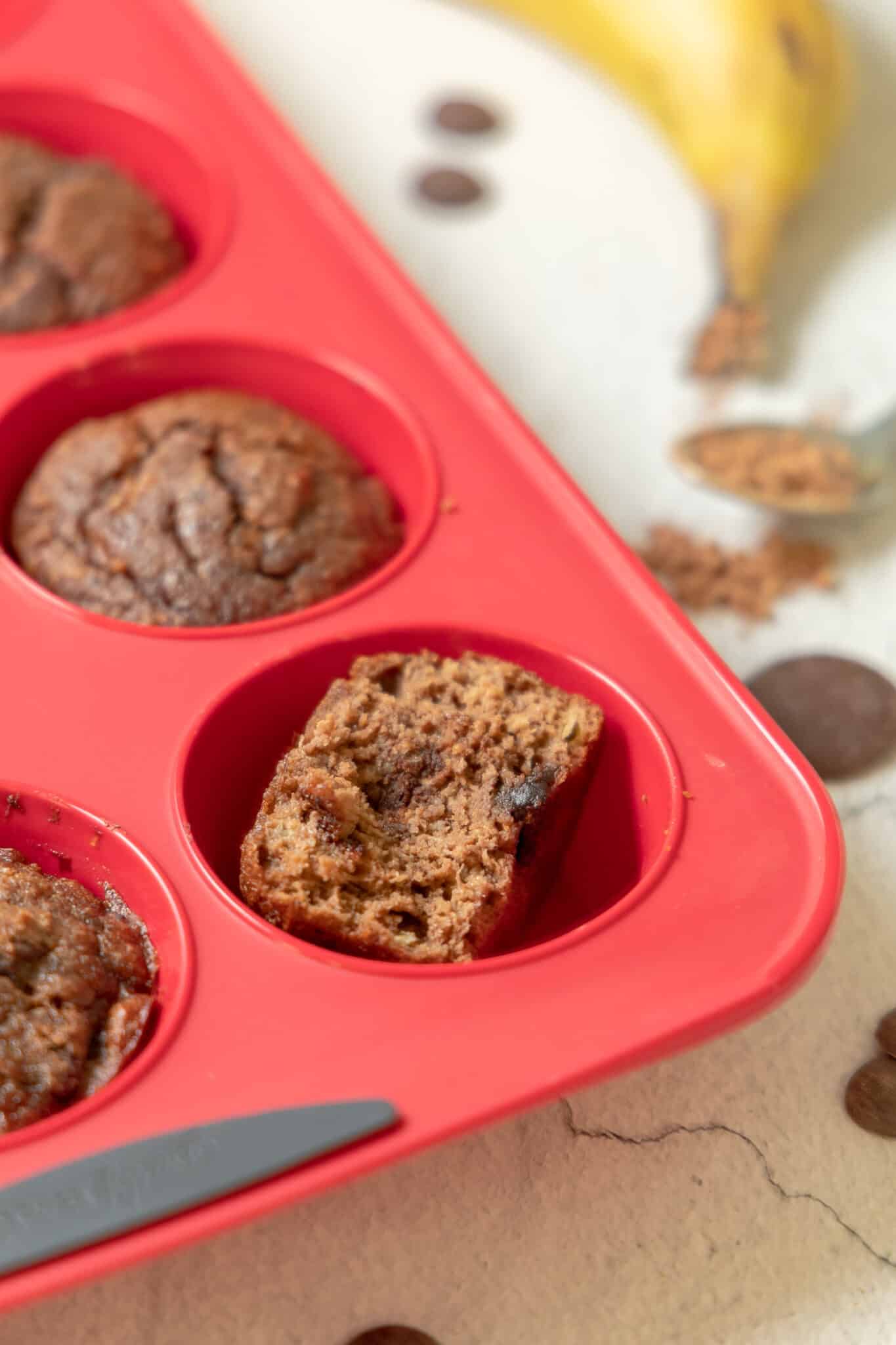 Cooked muffins in muffin tray with one muffin cut in half.