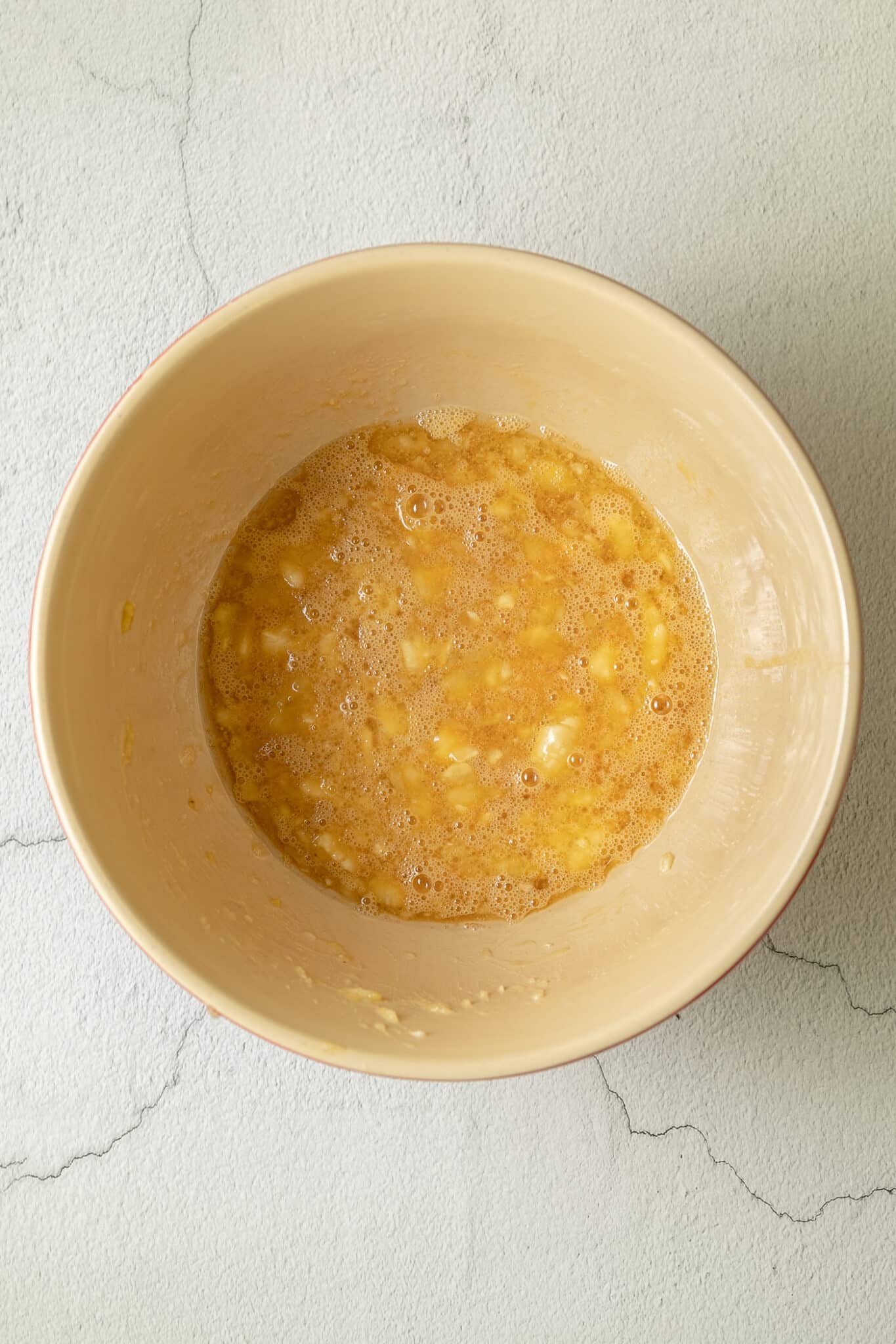 bowl with the eggs, coconut oil, maple syrup, vanilla extract and mashed bananas mixed together