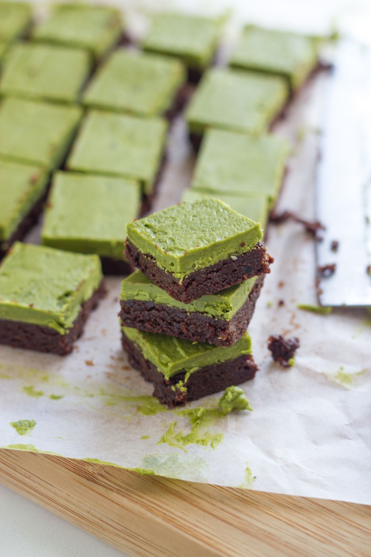 Three matcha brownies bars stacked on top of each other with the remaining pieces behind.