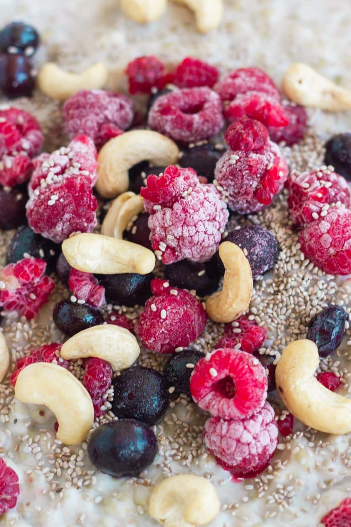 Raspberries, blueberries, cashews, chia seeds on top of porridge.