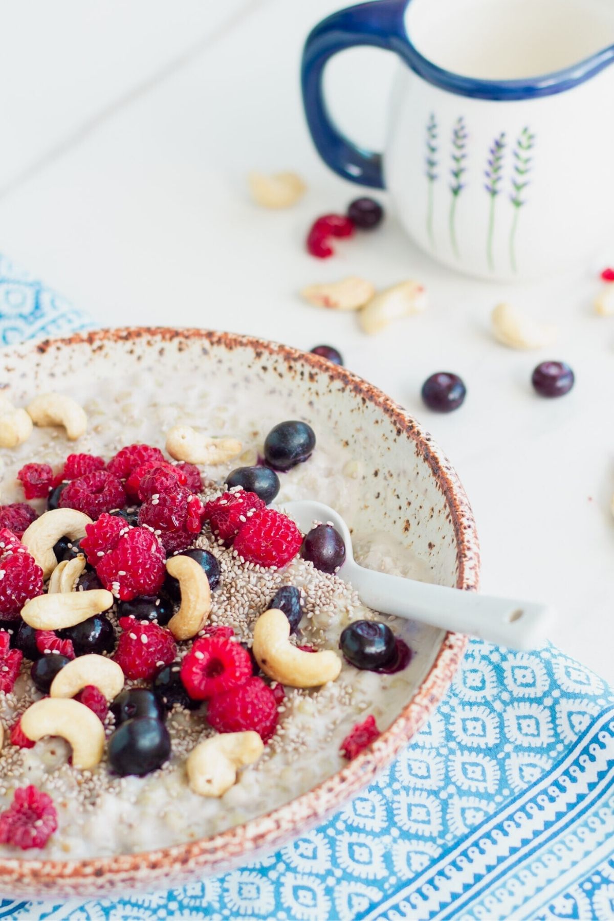 Bowl of buckwheat porridge topped with raspberries, blueberries, cashews and chia seeds.