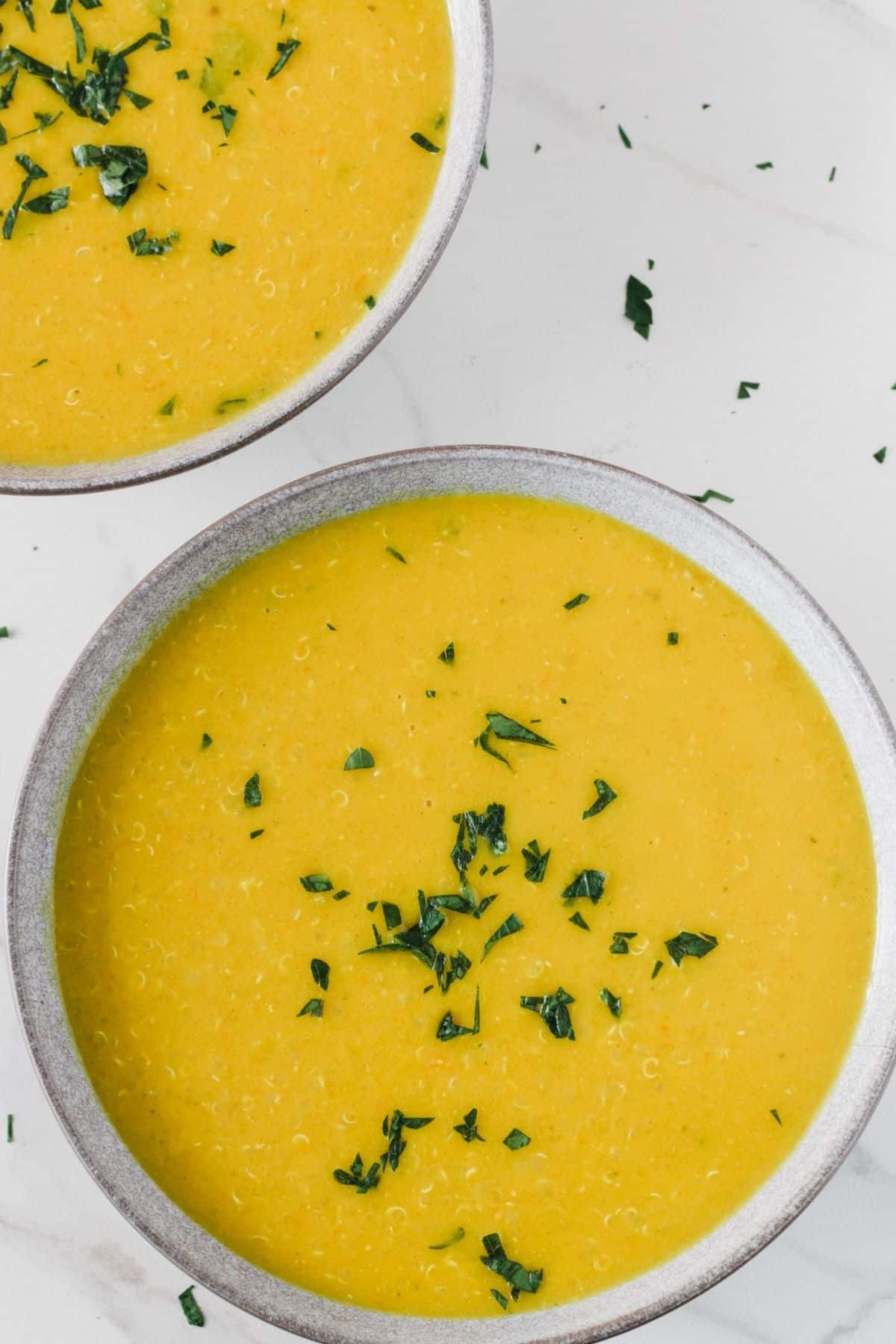 A bowl of middle eastern lentil soup next to another bowl.