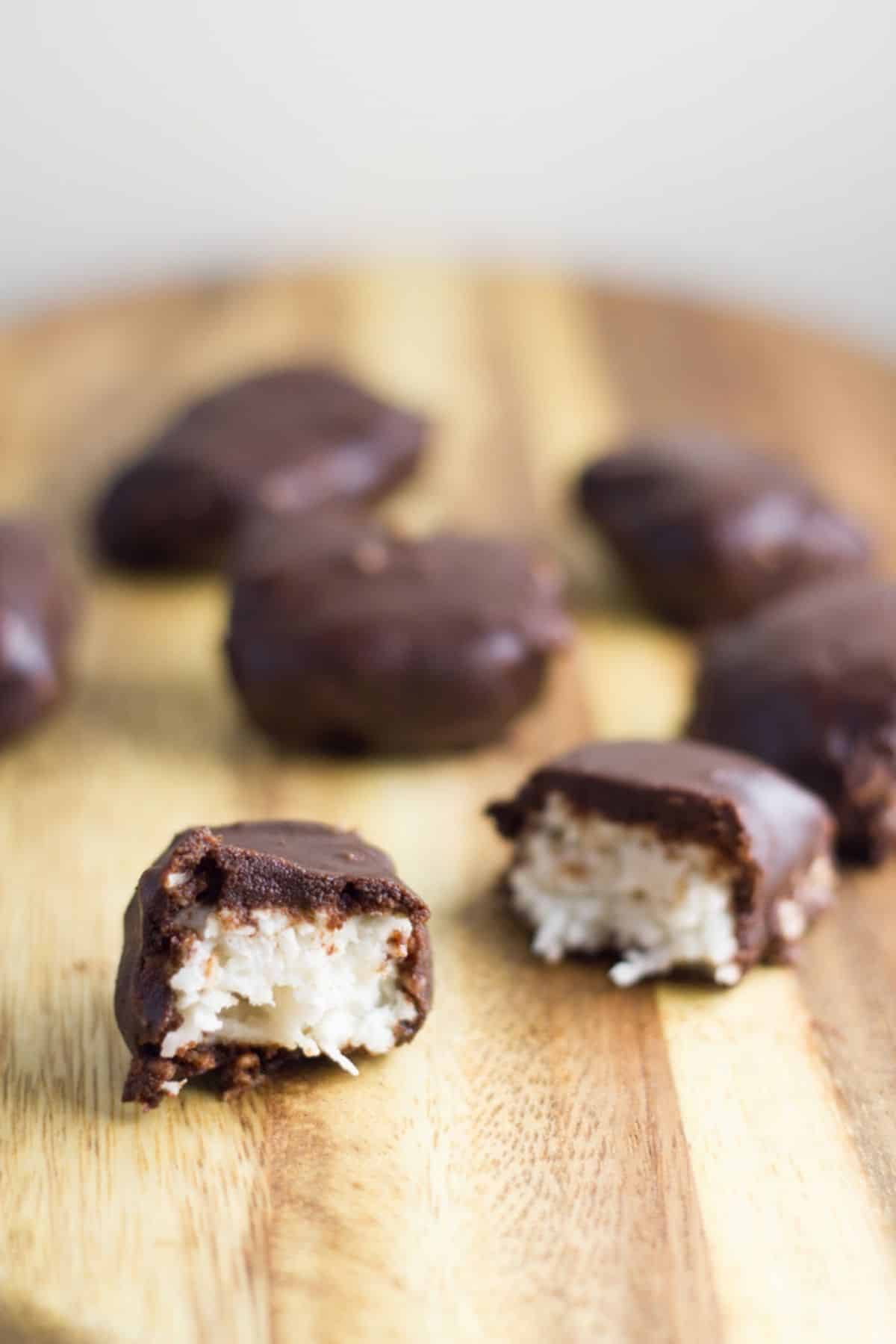 No-bake Chocolate Coconut Bars on a wooden board with two of them sliced showing the coconut inside.