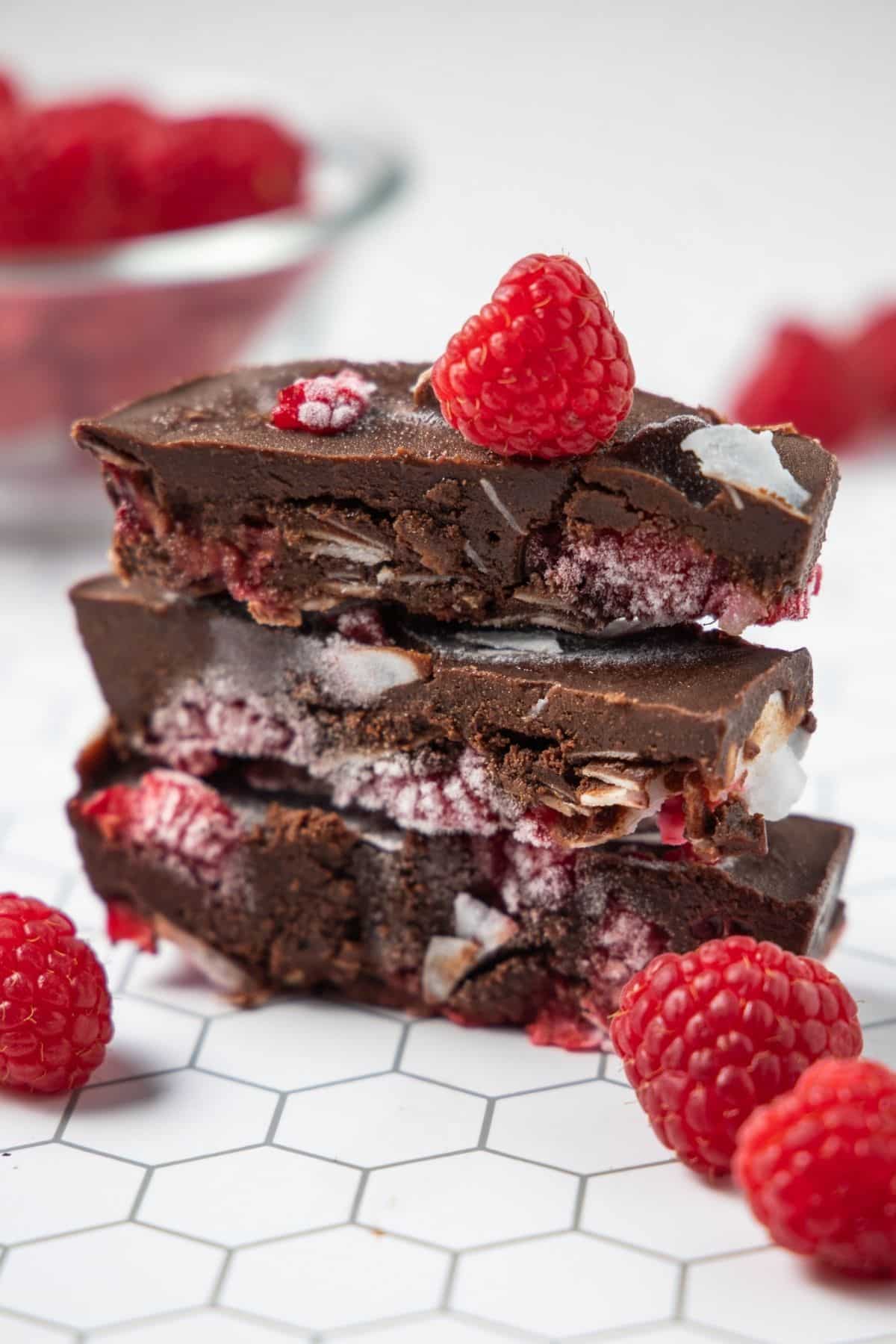 stack of raspberry chocolate bars with some fresh raspberries.