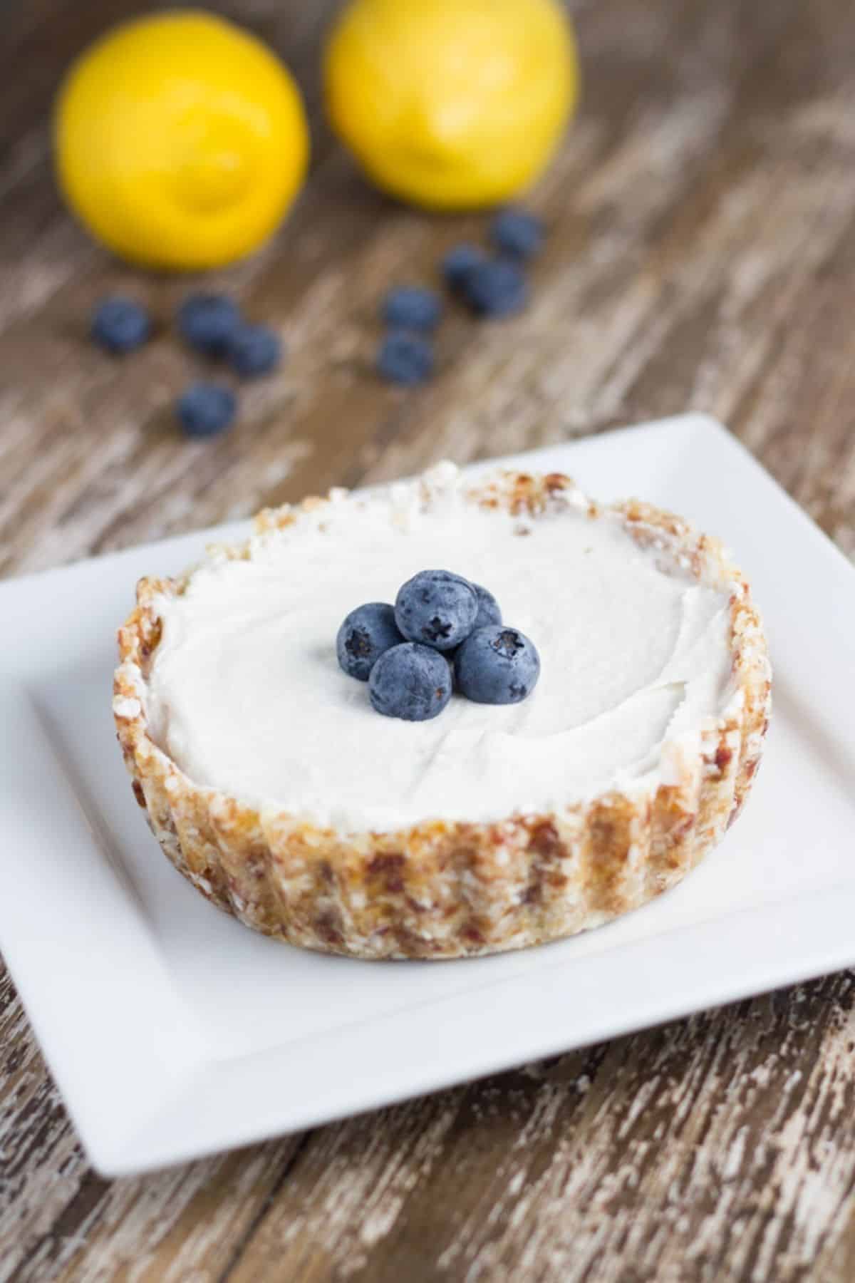 Vegan Lemon tart with some blueberries on top of a white plate